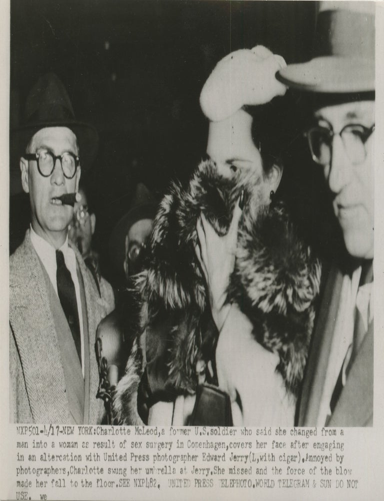 Item #List3891 1954 Press Photograph of Charlotte McLeod Shielding Her Face from New York Photographers After Her Return from Denmark. LGBTQ+ History &ndash; Transgender History &ndash; Press Photography, Charlotte McLeod.